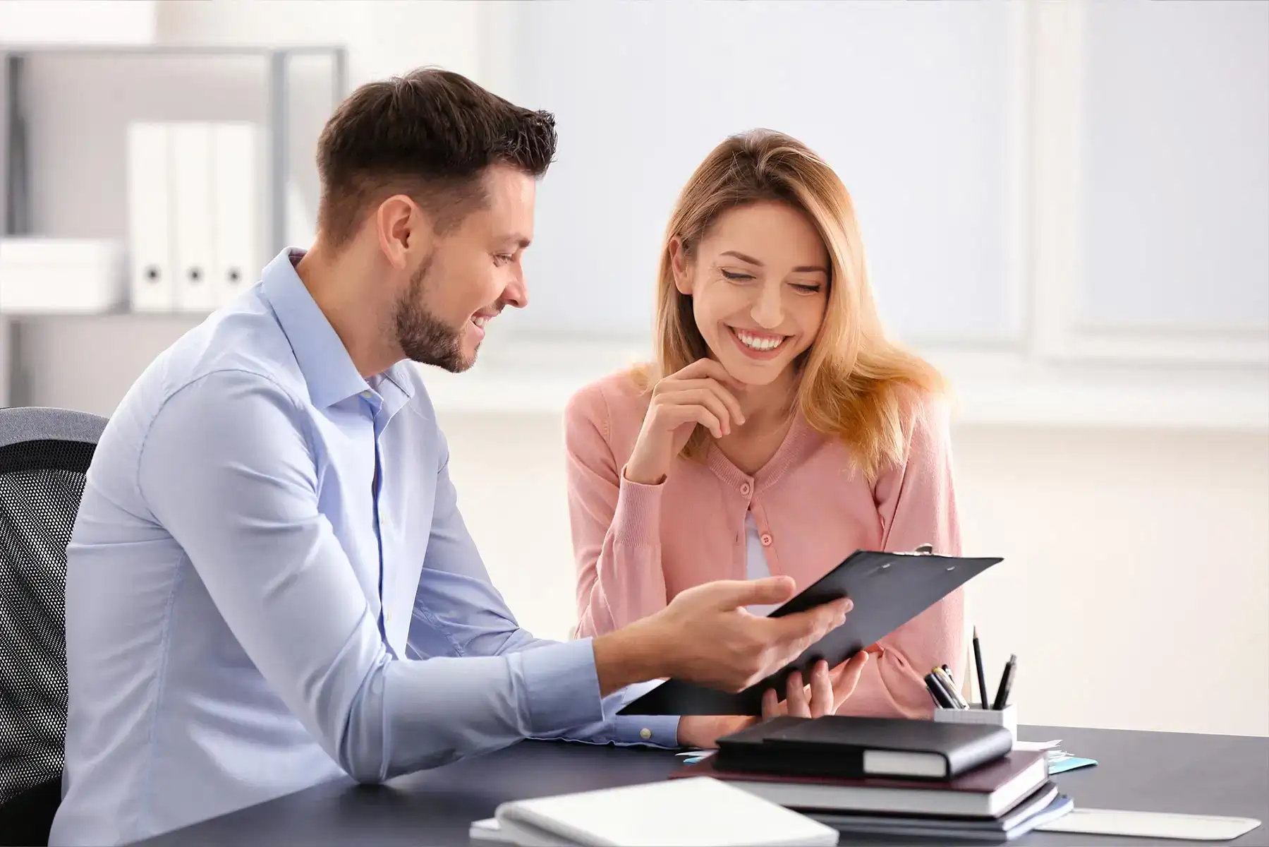 Un consulente mostra dei documenti su una tavoletta a una cliente sorridente durante un colloquio in ufficio